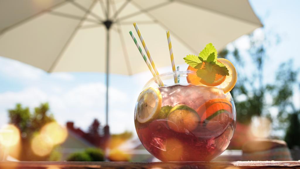 Ein großes Glas Sangria steht auf einem Tisch in sommerlicher Atmosphäre.