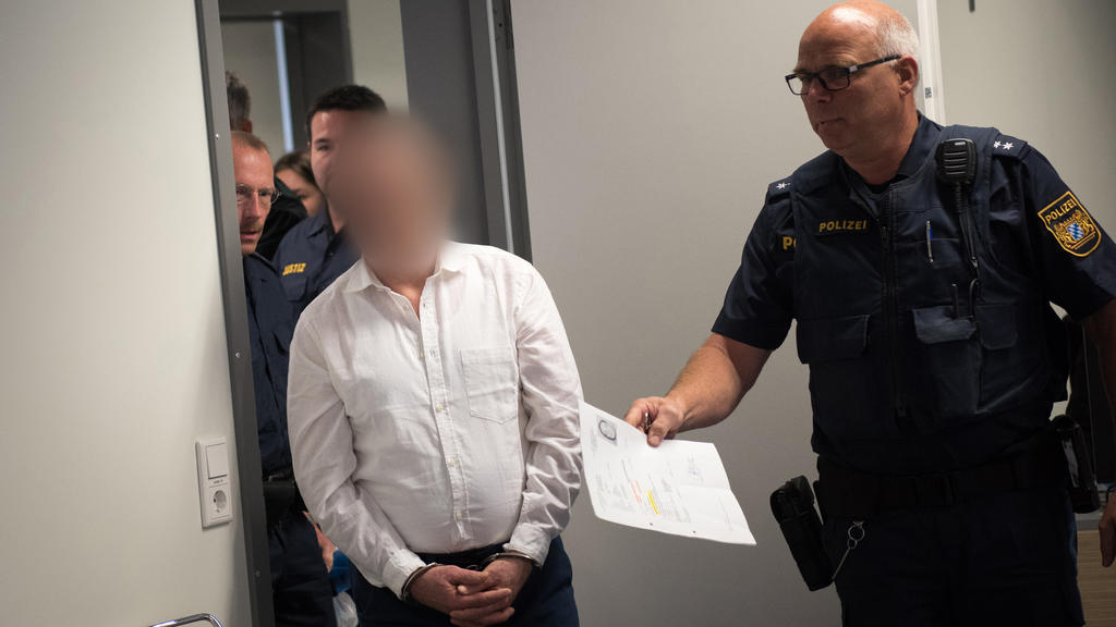 22.05.2018, Bayern, Aschaffenburg: Der Angeklagte (M) wird in den Gerichtssaal geleitet. Dreißig Jahre nach der Tat steht der 55 Jahre alte Mann wegen versuchten Mordes vor Gericht. Er soll 1988 eine junge Frau aus dem Raum Offenbach erst stundenlang