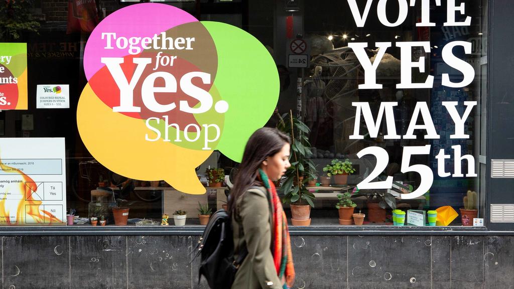 24.05.2018, Irland, Dublin: Eine Passantin geht an einem Schaufenster im Stadtteil Temple Bar vorbei, in dem dafür geworben wird, beim Referendum für die Abschaffung des Verfassungszusatzes zum Abtreibungsverbot zu stimmen. Am 25. Mai findet in Irlan