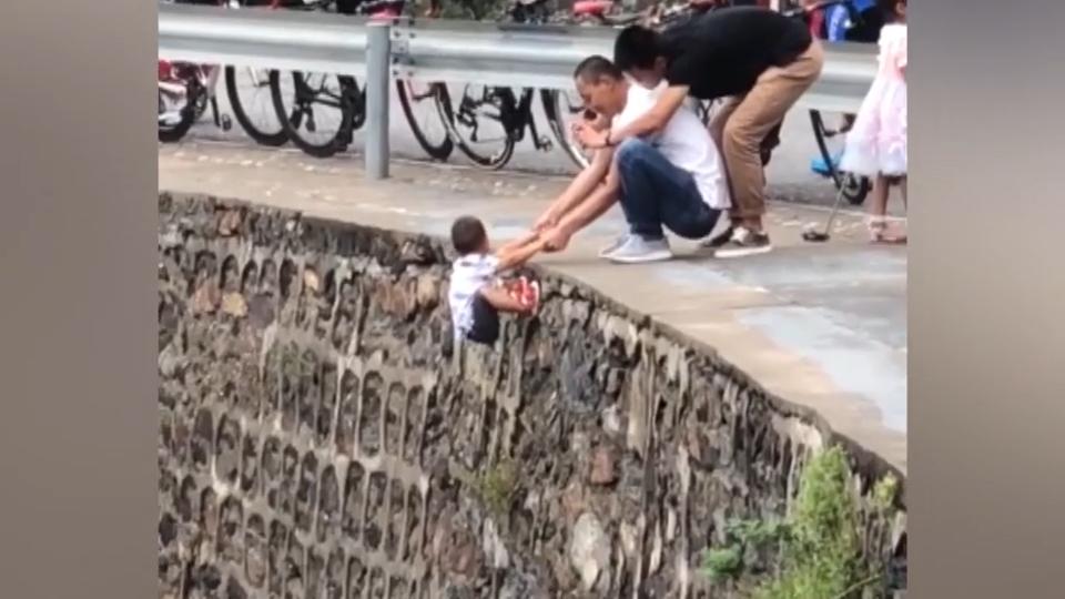 Mann hält sein Kind von einer Klippe für Fotos! Leichtsinnig