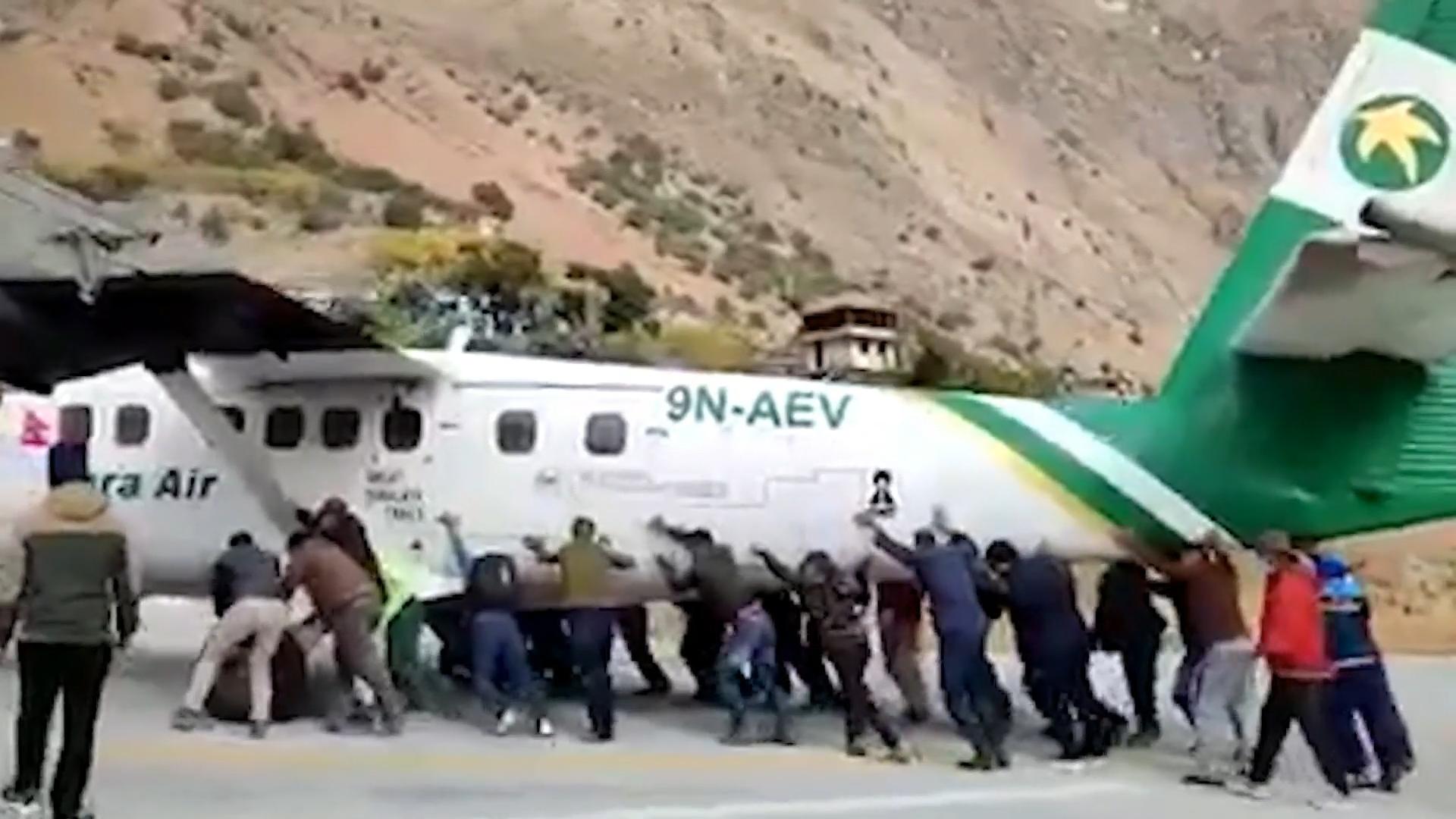 Passagiere schieben Flugzeug vom Rollfeld Nepal: Flugzeugreifen geplatzt