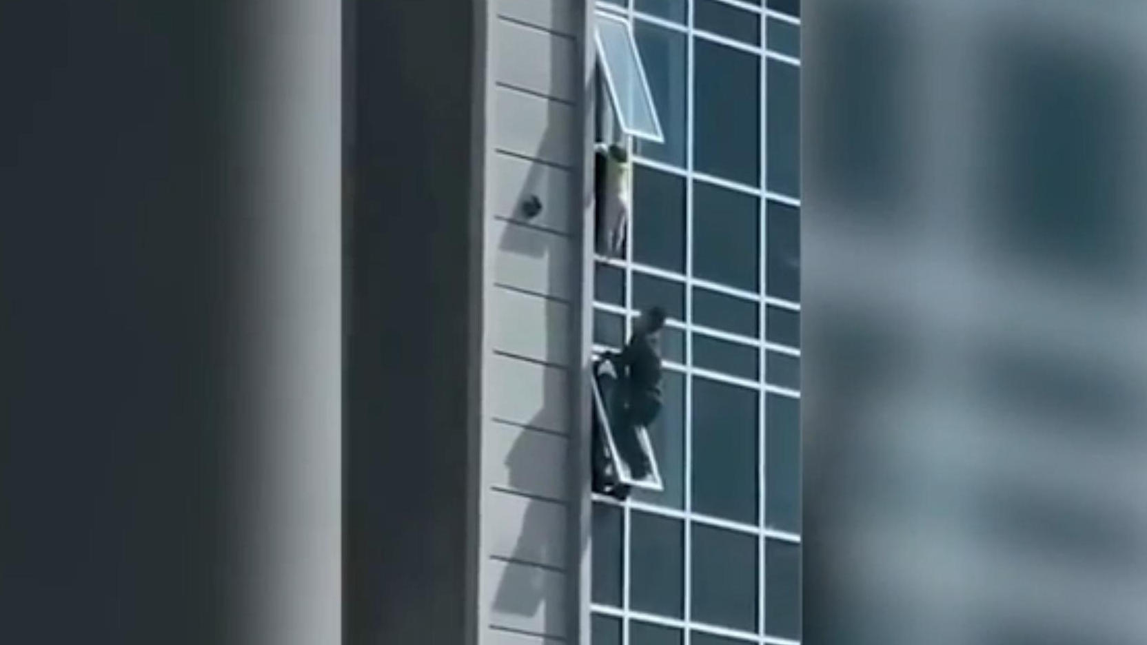 Kind baumelt aus Hochhaus-Fenster Dramatische Szenen