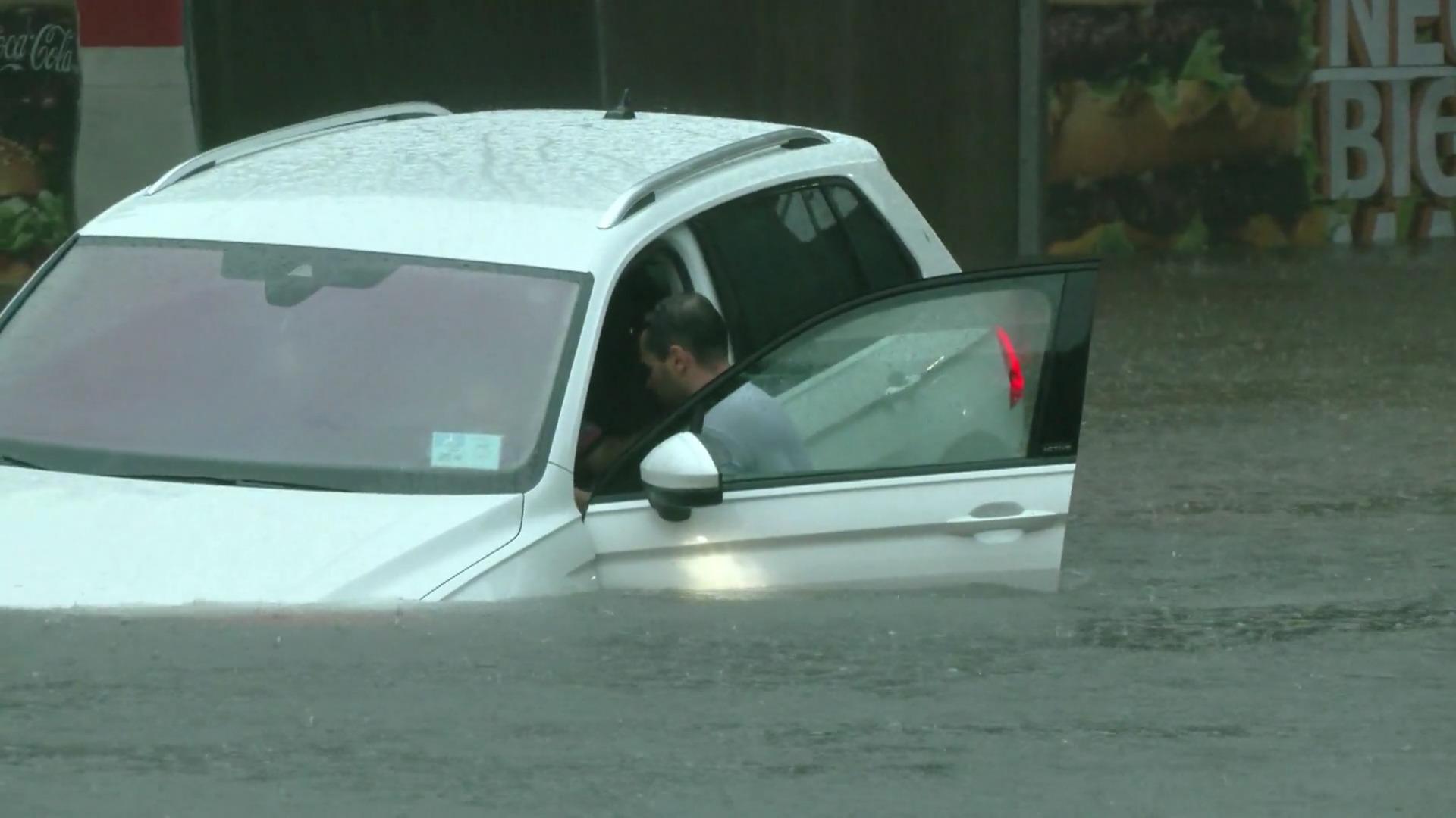 Orang-orang menyelamatkan diri dari tenggelamnya mobil.  Hujan deras: banjir Nuremberg